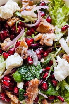 a salad with pomegranate, feta cheese and lettuce in it