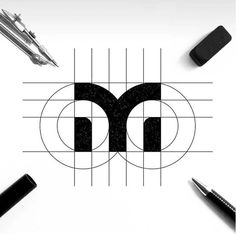 the letter m is surrounded by pens and pencils on top of a white surface