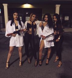 four women dressed in white and black posing for the camera with swords on their hands