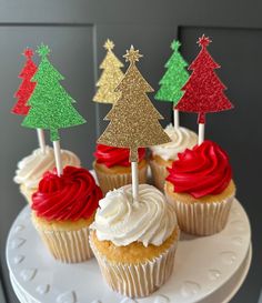 cupcakes decorated with red, green and gold frosting are sitting on a cake plate