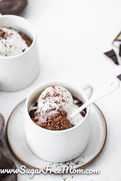 two white cups filled with dessert on top of a plate