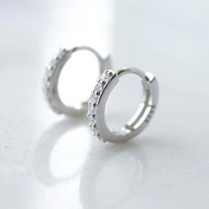 These dainty huggie hoop earrings are the perfect staple in anyone's jewellery box. Fit for any occasion, these hoops are made from sterling silver, with cubic zirconia stones.  Huggie hoops are small earrings that hug the ear, be sure to check the size listed below. Product details - * Sold as a pair * Made from 925 sterling silver * Finish - 925 sterling silver * Stone - cubic zirconia * Inner dimension - 9mm * Outer dimension - 11.2mm Please note: earrings are non-returnable due to hygiene reasons. Packaging - Your purchase will be posted to you in a cute reusable Riptide 5 cotton pouch, within a letterbox size mailing box, so there's no need to wait in for your order. If you order multiple items from the store and need extra cotton pouches (to give as gifts, etc) please leave a message Everyday Silver Hoop Earrings With Prong Setting, Silver Hypoallergenic Huggie Earrings For Weddings, Nickel-free Huggie Earrings For Anniversary, Dainty Silver Huggie Earrings, Silver Huggie Earrings For Wedding, Hypoallergenic Silver Huggie Earrings For Weddings, Minimalist Cubic Zirconia Huggie Earrings As Gift, Modern Huggie Earrings With Prong Setting As A Gift, White Gold Huggie Hoop Earrings For Gift