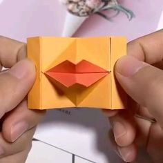 two hands are holding an origami piece