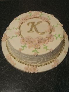 a three layer cake decorated with flowers and the letter k on it's side