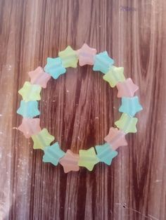 a close up of a bracelet made out of glass stars on a wooden table with wood grained background