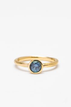 a gold ring with a blue topazte stone in the center on a white background