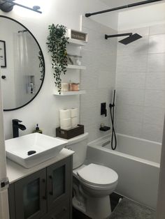 a white toilet sitting next to a bath tub under a bathroom mirror above a sink