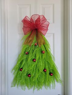 a christmas tree made out of green leaves and red balls hangs on the front door