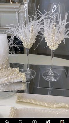 two wine glasses with pearls on them are sitting on a table next to some napkins