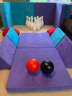 a bowling ball sitting on top of a purple mat next to a bowling pin with two red balls in it