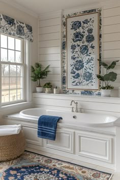 a white bath tub sitting under a window next to a rug and potted plant