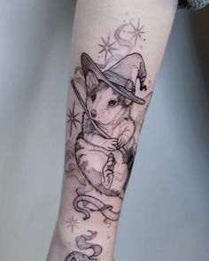 a tattoo on the leg of a woman wearing a hat and holding a wand in her hand