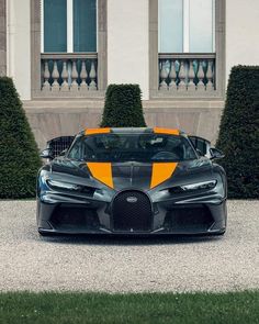 the bugatti supercar is parked in front of a building with two large windows