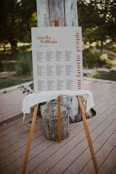 a wooden easel with a calendar on it sitting in front of a tree trunk