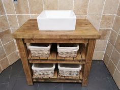 a wooden cabinet with baskets on top and a sink in the middle, next to a tiled wall