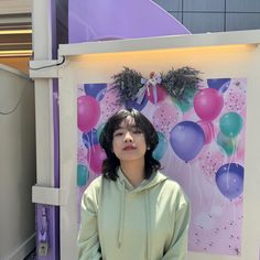 a woman standing in front of a wall with balloons on it