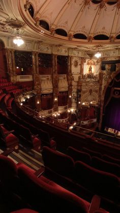 an empty theatre with red seats and chandeliers