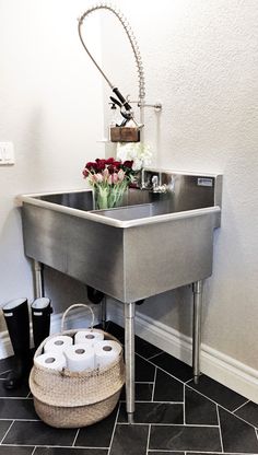 a bathroom sink with two rolls of toilet paper in it and some flowers on the counter