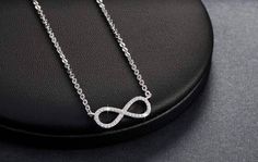 Centered between the two lengths of shiny silver tone chain, this miniature eternity symbol appears to float along the neck. Completely encrusted in micro CZ stones creating incredible shimmer. At only 2 cm this is truly subtle and graceful. This necklace is perfect for women, teens or young children. Length: 18 inch chain Stones: CZ Metal: Sterling Silver, 3 layers of platinum plating. Comes in a gift box. (Reg $45.99) White Gold Infinity Cubic Zirconia Jewelry, White Gold Infinity Jewelry With Cubic Zirconia, Silver Infinity Chain Jewelry, Dainty Infinity Silver Jewelry, Silver Infinity Clavicle Chain Jewelry, Dainty Silver Infinity Jewelry, Silver Infinity Clavicle Chain Necklace, Sterling Silver Infinity Jewelry For Parties, Silver Infinity Jewelry With Cubic Zirconia