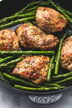 chicken and asparagus in a skillet on a marble countertop with the words,