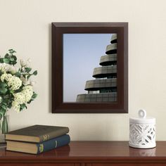 there is a vase with flowers on the table next to books and a framed photograph