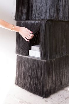 a woman's hand reaching for a piece of hair on top of a shelf