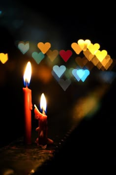 two lit candles with hearts in the background