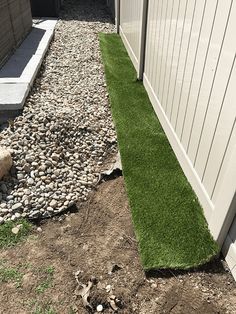 the grass is growing on the side of the house, and next to it is a rock bed