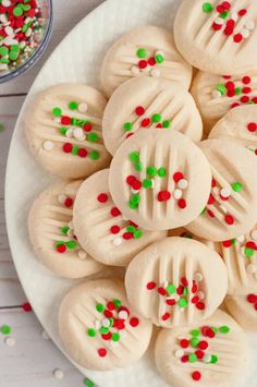 cookies decorated with white frosting and green and red sprinkles on a plate