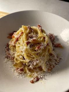 a white plate topped with pasta covered in sauce and parmesan cheese on top