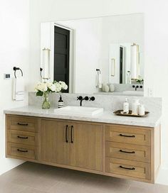 a bathroom vanity with two sinks and large mirror above it, along with other items on the counter