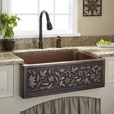 a kitchen sink with an ornate design on the front and side, under a window