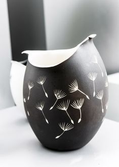 a black and white vase with dandelions on it's side sitting on a table