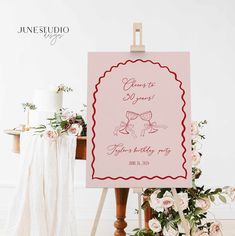 a pink sign sitting on top of a wooden easel next to a bouquet of flowers