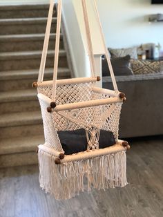 a hammock hanging from the ceiling in a living room with stairs leading up to it