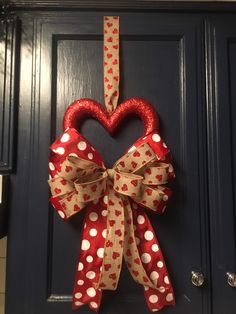 a red and white heart shaped bow hanging on a door with polka dot ribbon attached to it