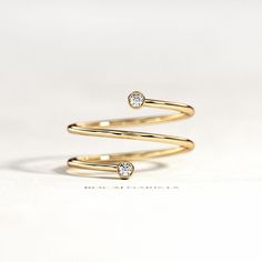 two gold rings with diamonds on them sitting next to each other in front of a white background