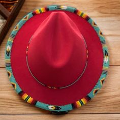 a red cowboy hat sitting on top of a wooden floor next to a box of chocolates