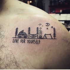 a man with a tattoo on his back that says live for yourself and camping is in the background