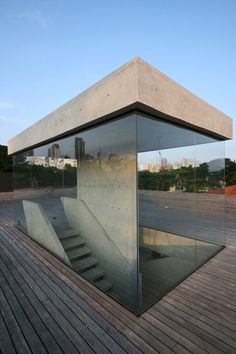 a glass box sitting on top of a wooden floor next to a building with stairs