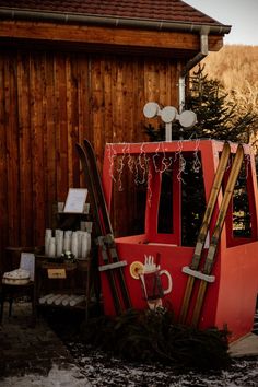 an old fashioned ski machine sitting in front of a wooden building with snow on the ground