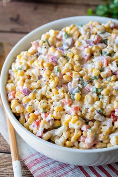 a white bowl filled with corn salad on top of a table