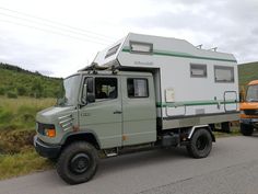 an off - road vehicle with a camper attached to the back is parked next to another truck