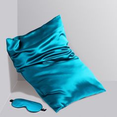 a blue pillow and eye mask on a white surface