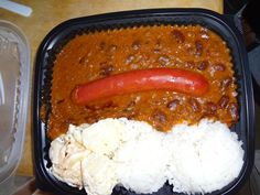 a plastic container filled with rice, beans and a hot dog