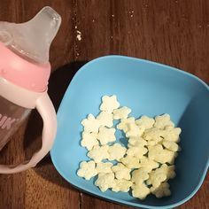 a blue bowl with marshmallows in it next to a sippy cup