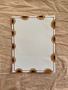 a square mirror sitting on top of a bed covered in sheets and paper with circles around it