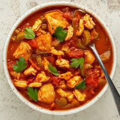 a white bowl filled with chicken and vegetable stew on top of a marble countertop