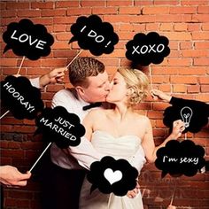 a man and woman kissing in front of a brick wall with speech bubbles attached to them