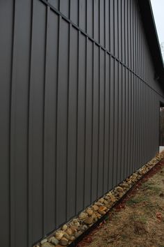 the side of a building that has some rocks on it and grass in front of it